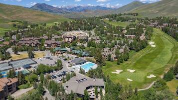 Eine Vogelperspektive zeigt eine Wohngegend mit Häusern, einen Golfplatz und Berge im Hintergrund.