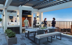 Eine Terrasse im Freien mit modernem Design, ausgestattet mit einer Essgruppe inklusive Tischen und Bänken, einem eingebauten Grill und Blick auf die Stadtlandschaft.