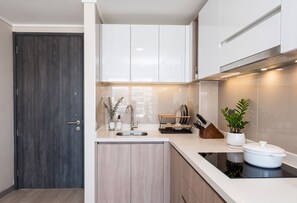 Eine moderne Küche mit weißen Schränken, einer Edelstahlspüle und einem eingebauten Backofen.
