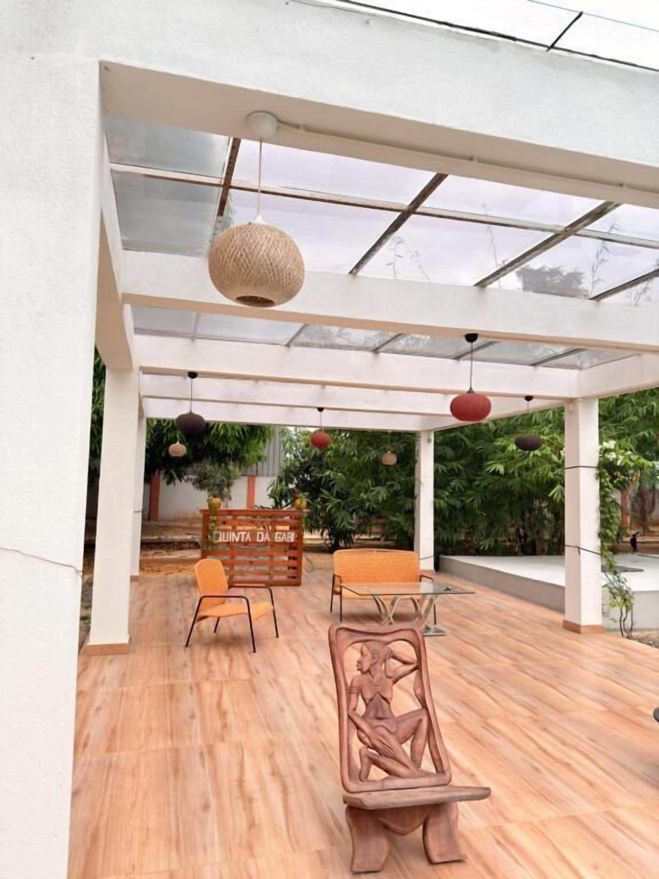 Un patio al aire libre con piso de madera, pérgola blanca y luces colgantes.