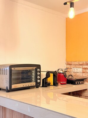 A kitchen with a vintage toaster, a red kettle, and a modern light fixture.
