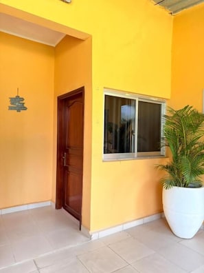 A building entrance with a wooden door, a window, and a potted plant.