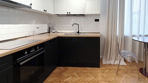 Una cocina moderna con armarios blancos, encimera negra y suelo de madera con estampado de espiga.