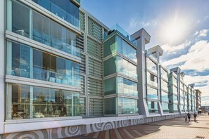 Ein modernes Gebäude mit großen Fenstern, einer gemusterten Eingangsebene und blauem Himmel.