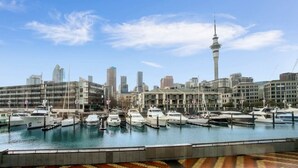 A marina with boats docked, a city skyline with modern buildings, and a prominent tower. - Smart Compact Two Bedrooms 2 Bath & Two Balconies (Auckland City)