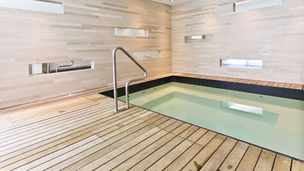 A modern indoor swimming pool with wooden flooring and a metal ladder. - Smart Compact Two Bedrooms 2 Bath & Two Balconies (Auckland City)