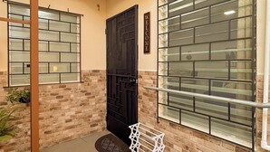 A residential building with a brick facade, a black door, and a window with a metal grid. - Charming 1BR Home Near Downtown SS & Metrocentro (San Salvador)