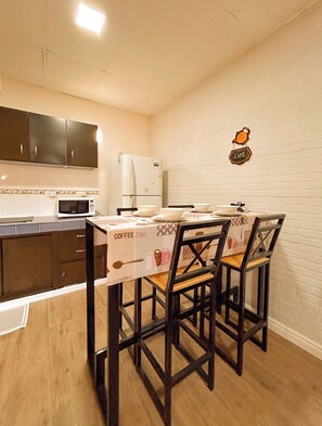Une cuisine de taille réduite comprenant une table à manger, des chaises et un réfrigérateur.
