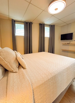 A hotel room with a bed, curtains, a television, and a window. - Charming 1BR Home Near Downtown SS & Metrocentro (San Salvador)