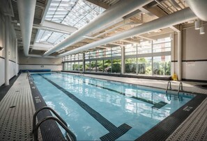 An indoor swimming pool with clear glass walls, a tiled floor, and a ceiling with visible ductwork. - Downtown Vancouver, Sleeps 7, Pool & Hot Tub (Vancouver)