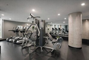 Ein Fitnessstudio mit Laufbändern, Crosstrainern und Gewichten.