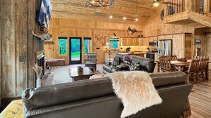 A rustic cabin interior with a living room, dining area, and kitchen. - Spur and Arrow - Parade of Homes Cabin | Screened Porch and Hot Tub | Firepit (Morganton)