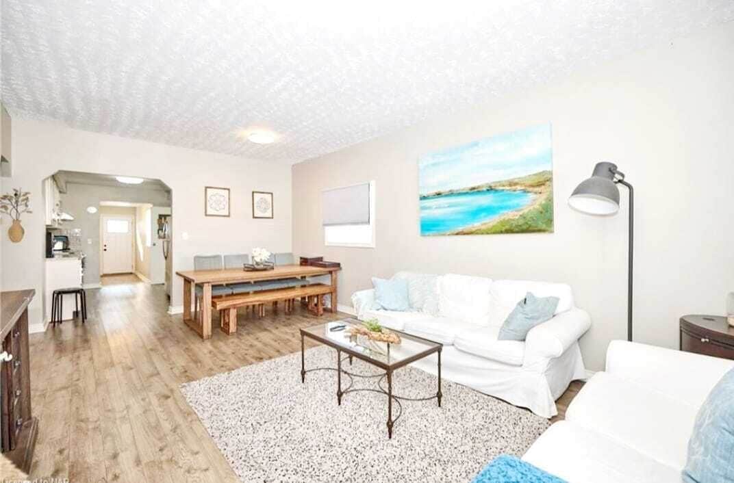 A living room with a white sofa, a coffee table, and a painting on the wall.