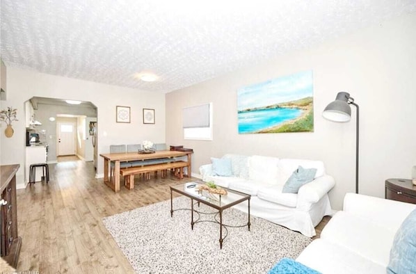 A living room with a white sofa, a coffee table, and a painting on the wall.