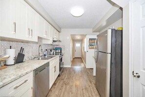 A kitchen with white cabinets, a granite countertop, and a stainless steel refrigerator. - Massive Family Home Minutes from Niagara Falls (Niagara Falls)