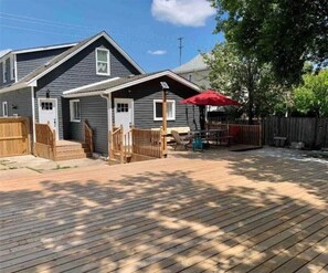 A residential deck with a wooden floor, a red umbrella, and a wooden fence.