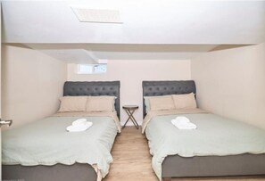 A room with two beds, each with a headboard, a small table, and a window. - Massive Family Home Minutes from Niagara Falls (Niagara Falls)