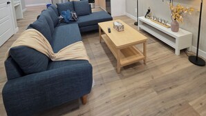 Ein modernes Wohnzimmer mit einem Ecksofa, einem Holztisch und einem flachbildfernseher an der Wand.