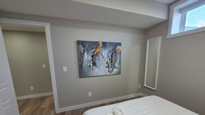 Ein Schlafzimmer mit einem Bett, einem Bild an der Wand und einem Fenster.