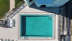 Vista aerea di una piscina rettangolare con bordo piastrellato, dotata di lettini e scala.