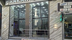 A hotel entrance with a marble facade, a glass door, and a signboard displaying brand logos.