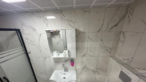 A bathroom with a glass shower enclosure, a white sink with a mirror above it, and a toilet.