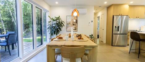 A modern kitchen with a large island, stainless steel appliances, and a view of the outdoors.