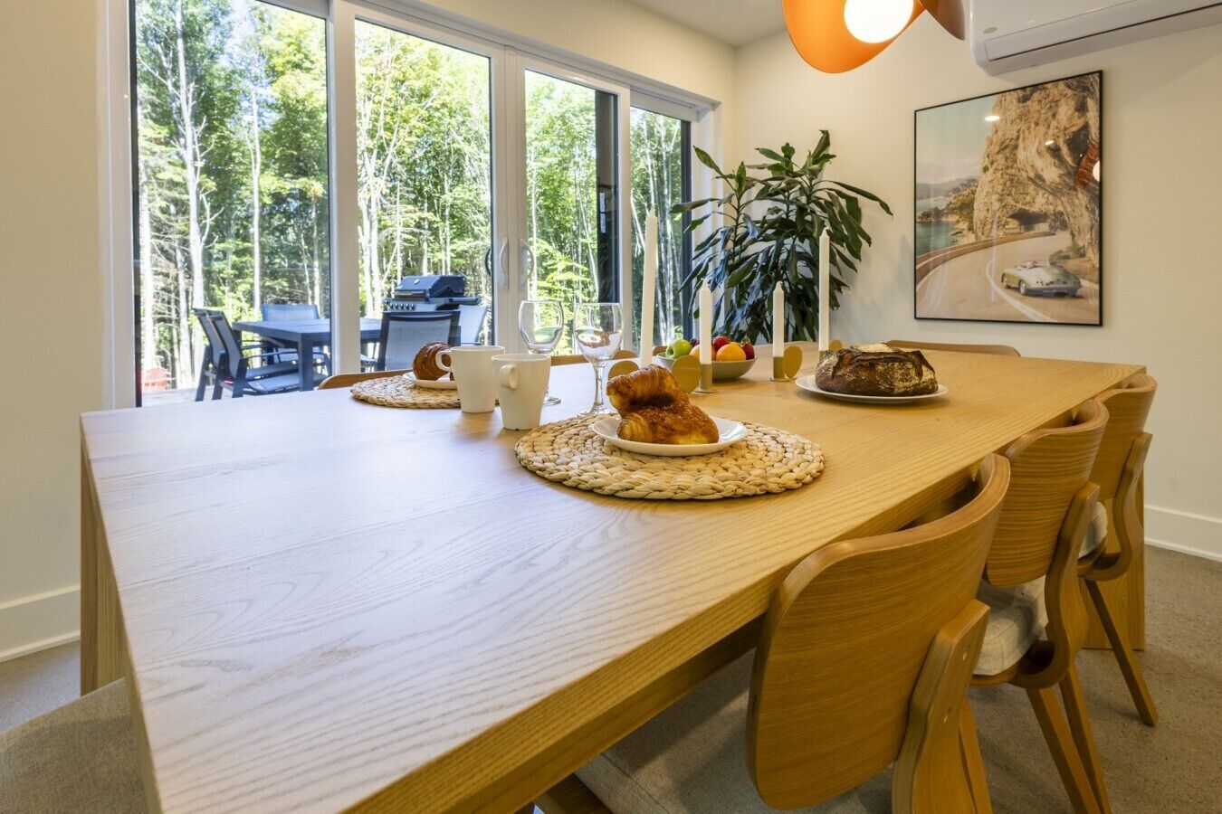 A dining area with a wooden table, chairs, and a painting on the wall.