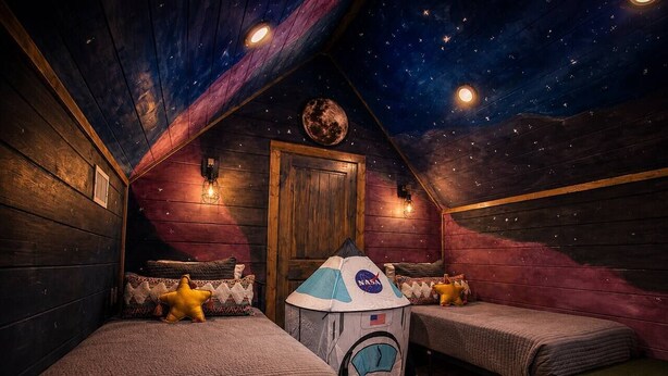 Ein Zimmer mit zwei Betten, einem Raumschiff-Zelt von NASA und einer Sternenhimmel-Decke.