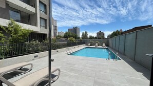 A rooftop pool with lounge chairs, a view of the cityscape, and a clear sky. - Stgo Metro A. Hurtado - Domus Travels (Santiago)