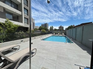 A rooftop pool with lounge chairs, a view of the cityscape, and a clear sky. - Stgo Metro A. Hurtado - Domus Travels (Santiago)
