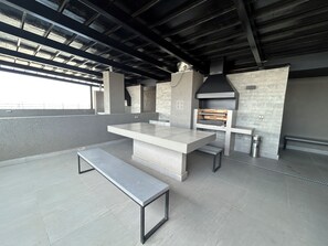 An outdoor kitchen area with a built-in oven, a long bench, and a tiled floor. - Eco Estación Santiago by Domus Travels (Santiago)