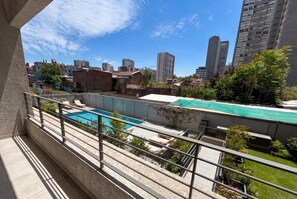 A residential area with a swimming pool, a brick building, and high-rise buildings in the background. - Eco Estación Santiago by Domus Travels (Santiago)