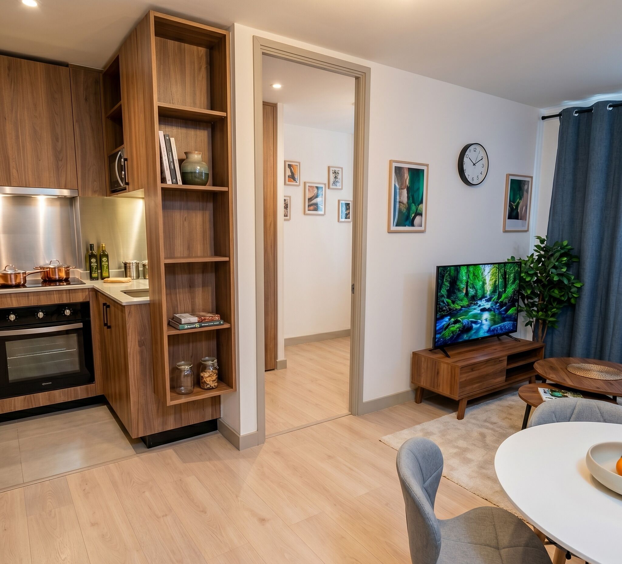 Una cucina moderna con mobili in legno, un forno integrato e un'area pranzo con tavolo e sedie bianche.