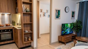 A modern kitchen with wooden cabinets, a built-in oven, and a dining area with a white table and chairs. - Stgo Metro A. Hurtado - Domus Travels (Santiago)