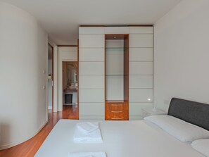 A modern hotel room with a large bed, a bedside table, a mirror, and a wardrobe. - Caminito by Interhome (Riva del Garda)