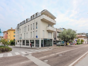 Ein modernes mehrgeschossiges Gebäude mit Eingang im Erdgeschoss, großen Fenstern und einer Fußgängerüberweg.