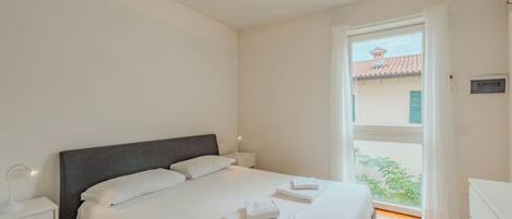 A bedroom with a bed, bedside tables, and a window with a view.
