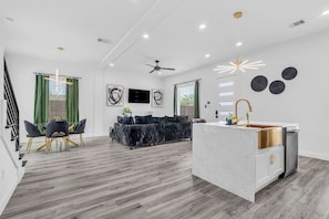 A modern kitchen with a marble countertop, a built-in oven, and a stainless steel refrigerator. - The Emerald Noir (Houston)