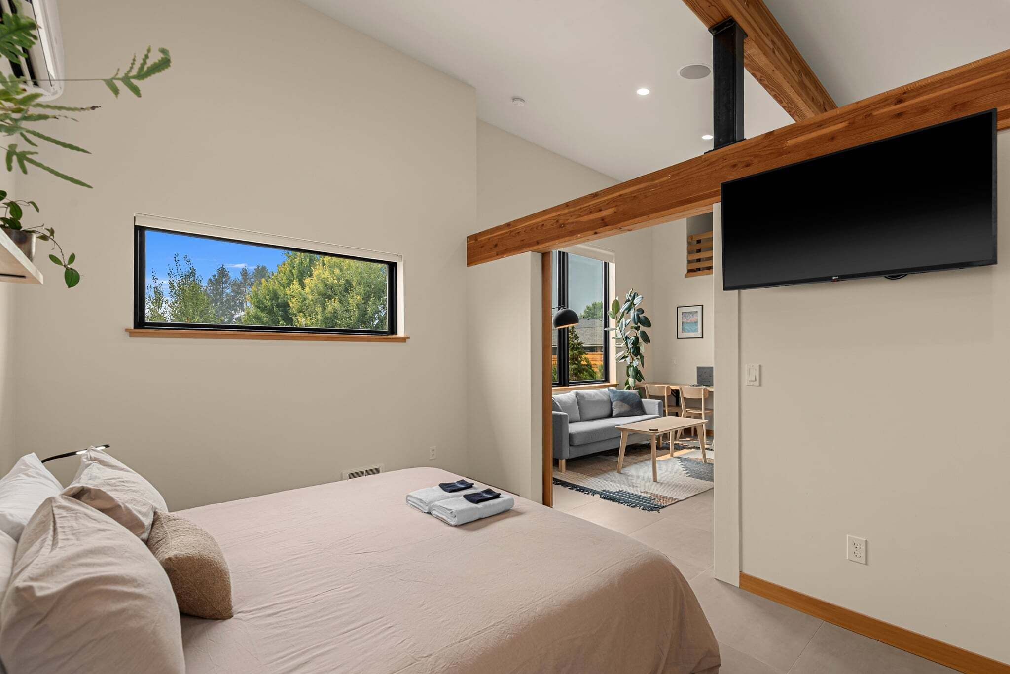 Une chambre à coucher avec un lit, une télévision et une fenêtre donnant sur des arbres.