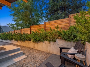 A patio with a concrete wall, wooden fence, and a seating area with a table and chairs.