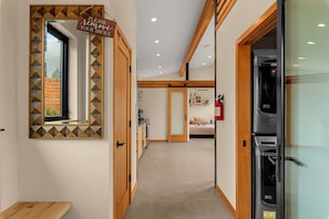A corridor with a sign instructing to remove shoes, leading to a kitchen area with a refrigerator and a dining area.