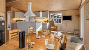 Een gezellig eetgedeelte met een houten tafel, stoelen en een koffiepot.