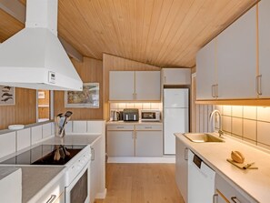 A modern kitchen with white cabinetry, a built-in oven, a microwave, and a sink.