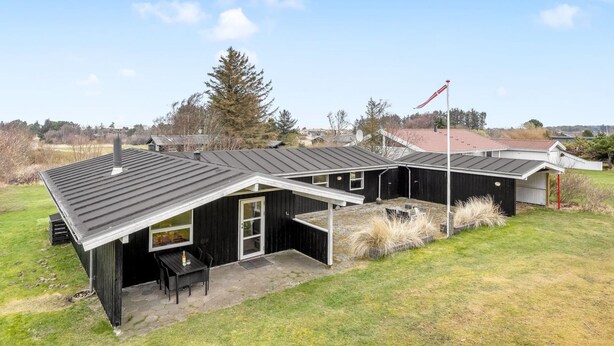 Een huis met twee verdiepingen, een overdekte veranda en een vlaggenmast.
