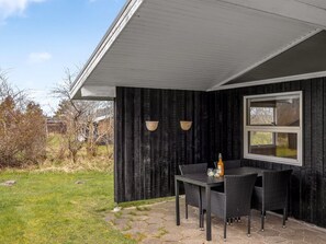 An outdoor patio with a table and chairs, a bottle, and two wall-mounted lights.