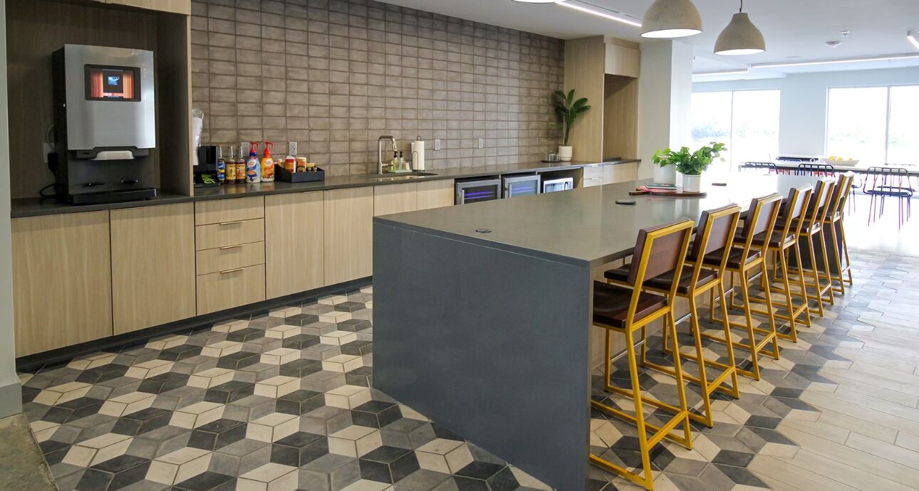 Une cuisine moderne dotée d’un îlot central, de tabourets de bar et d’un sol carrelé.