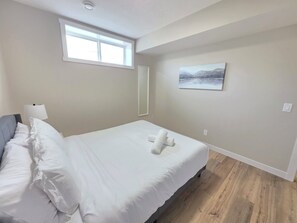 A hotel room with a bed, a window, a painting, and a lamp. - Charming 2-bedroom Basement Suite in Calgary with AC (Calgary)