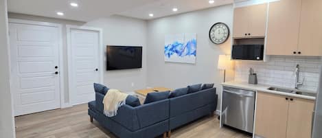 Un salon moderne avec un canapé, un téléviseur à écran plat et une horloge au mur.