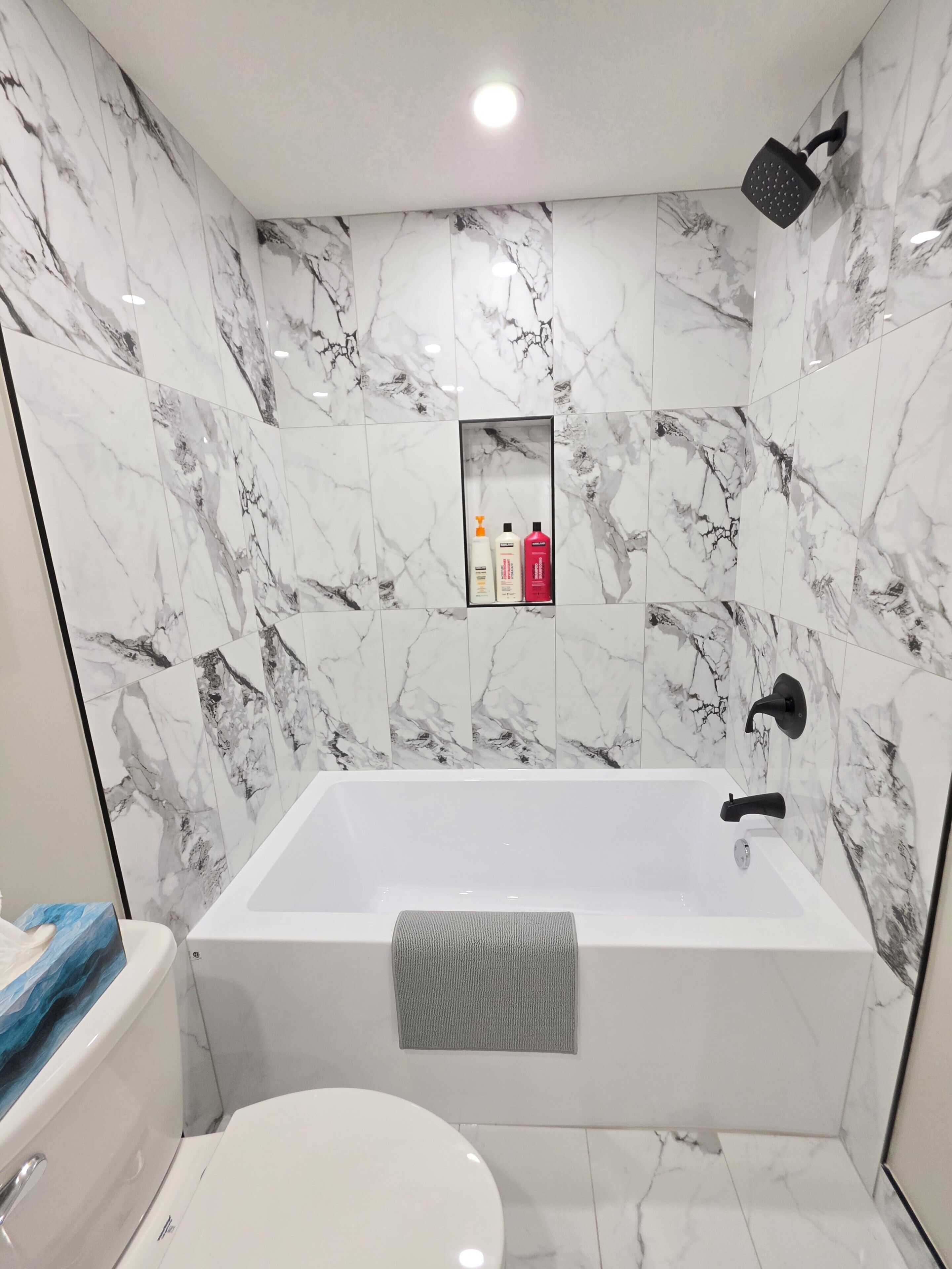 Une salle de bain avec une baignoire blanche, des toilettes et une pomme de douche.